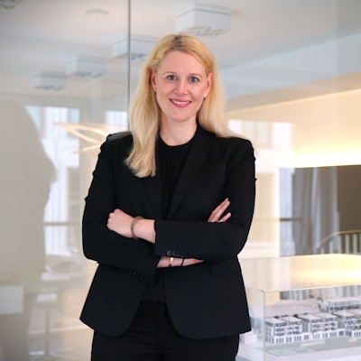 Britta Oebels steht in einem Konferenzraum ihres Hauptgeschäfts am Kaiser-Wilhelm-Ring. Im Hintergrund ein Modell eines Immobilenentwurfs