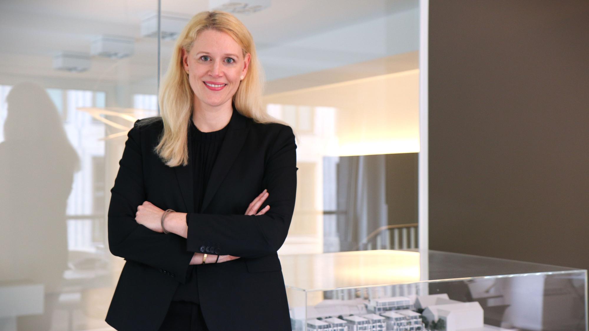 Britta Oebels steht in einem Konferenzraum ihres Hauptgeschäfts am Kaiser-Wilhelm-Ring. Im Hintergrund ein Modell eines Immobilenentwurfs