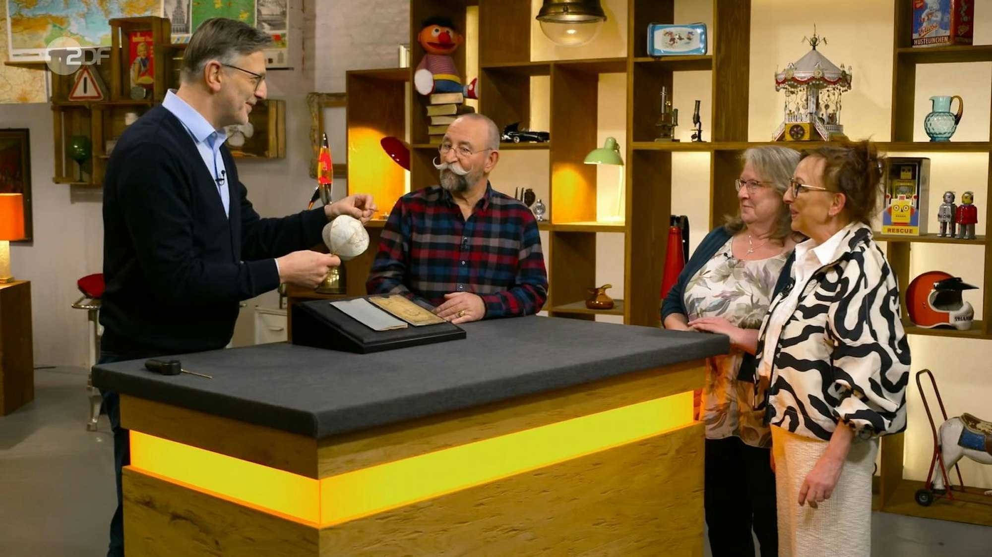 Der faltbare Globus hat es den Verkäuferinnen ebenso angetan wie Experte Detlev Kümmel (links) und Moderator Horst Lichter. (Bild: ZDF)