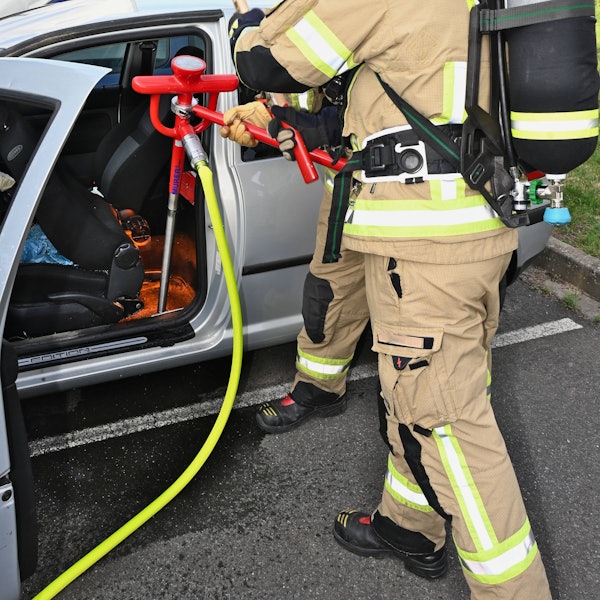 Feuerwehrleute löschen eine brennende Batterie in einem Elektrofahrzeug.