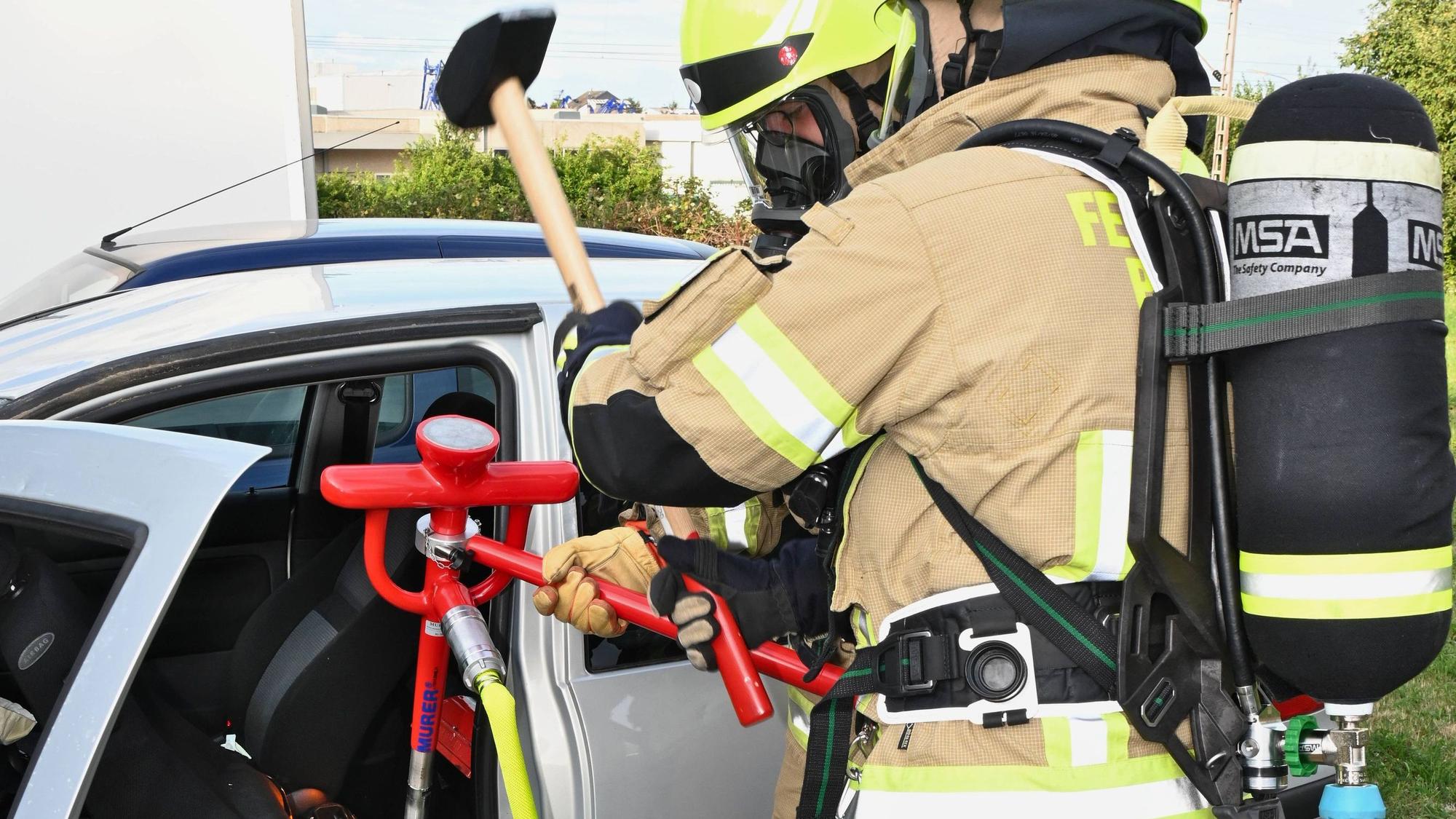 Feuerwehrleute löschen eine brennende Batterie in einem Elektrofahrzeug.