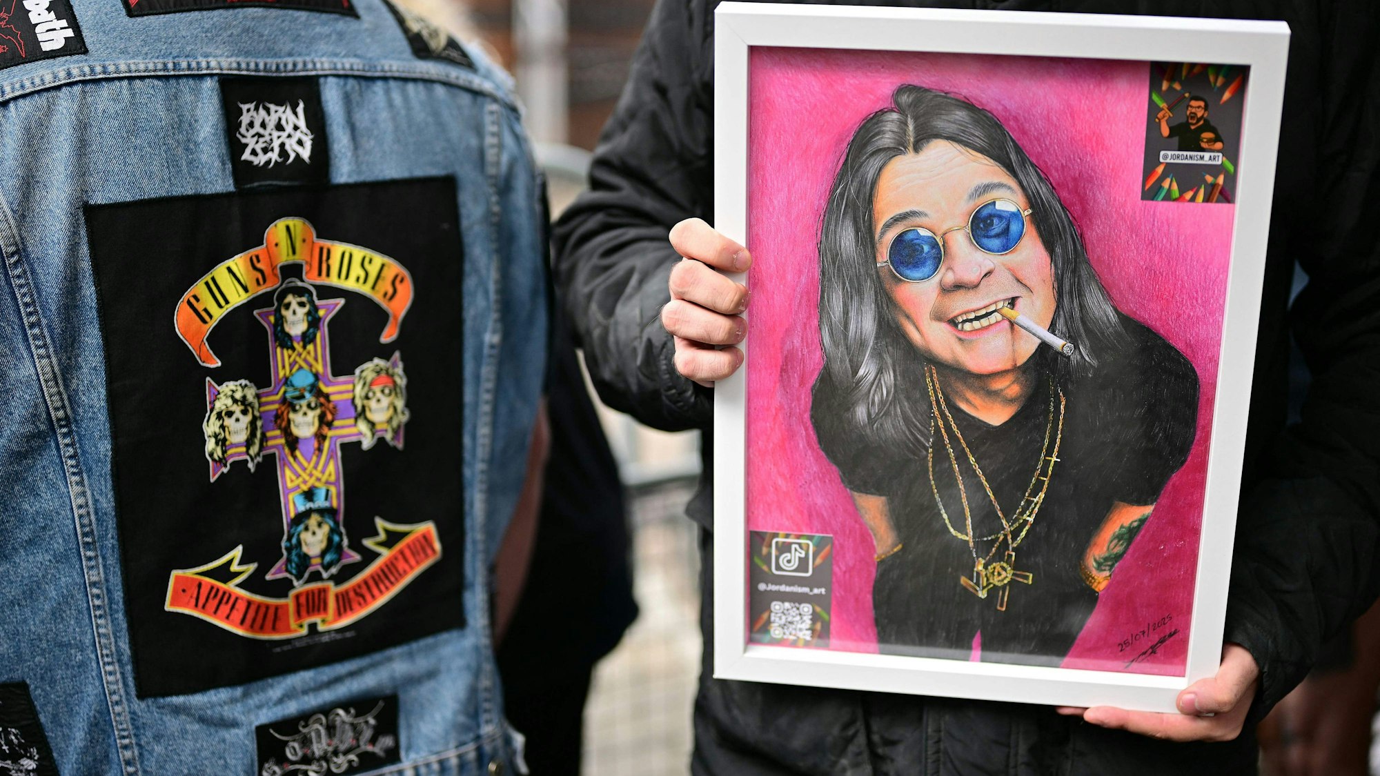 Ein Fan hält eine Zeichnung des verstorbenen Leadsängers von Black Sabbath, Ozzy Osbourne, in der Hand. Er hofft, sie der Frau des Sängers überreichen zu können, wenn der Leichenzug am 30. Juli 2025 durch Birmingham, Mittelengland, fährt.