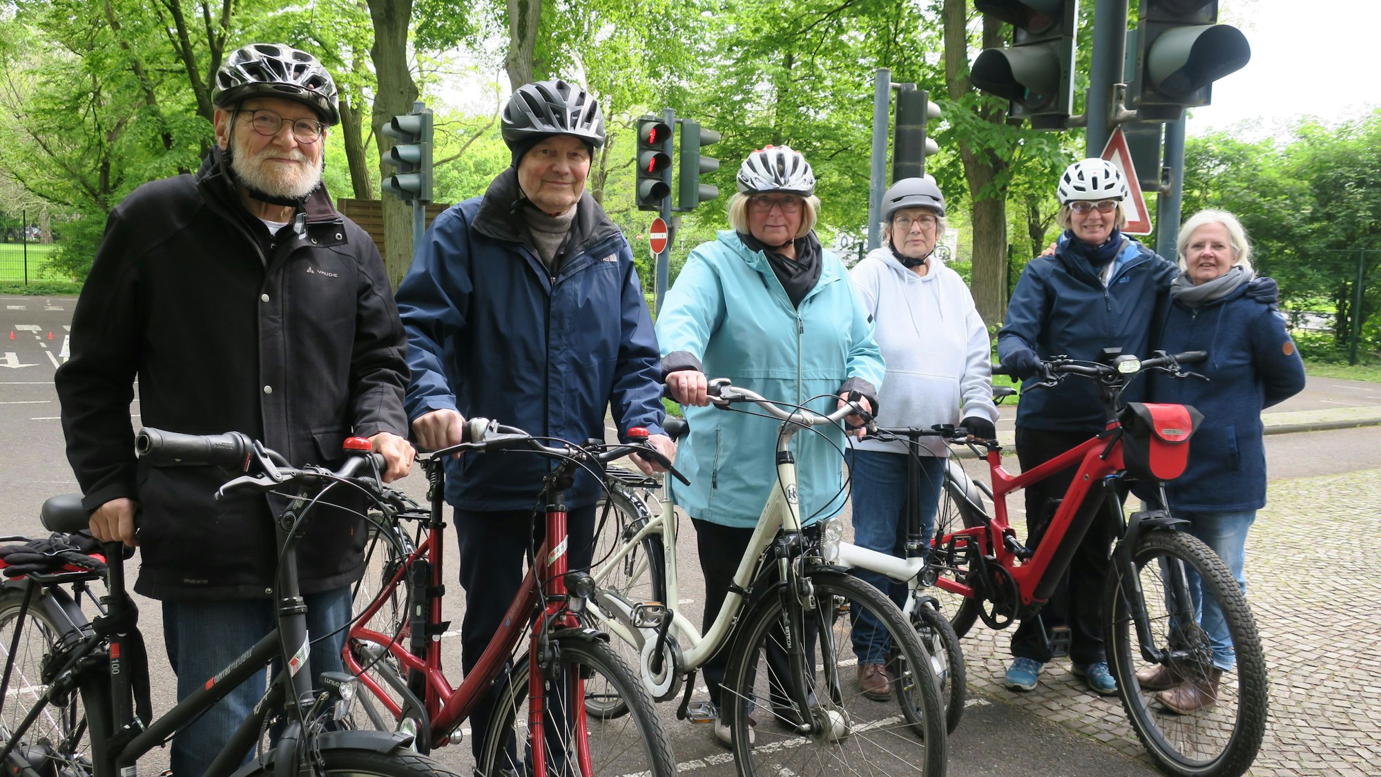 Senioren und Seniorinnen stehen mit Rädern und Helmen auf einem verkehrsübungsplatz
