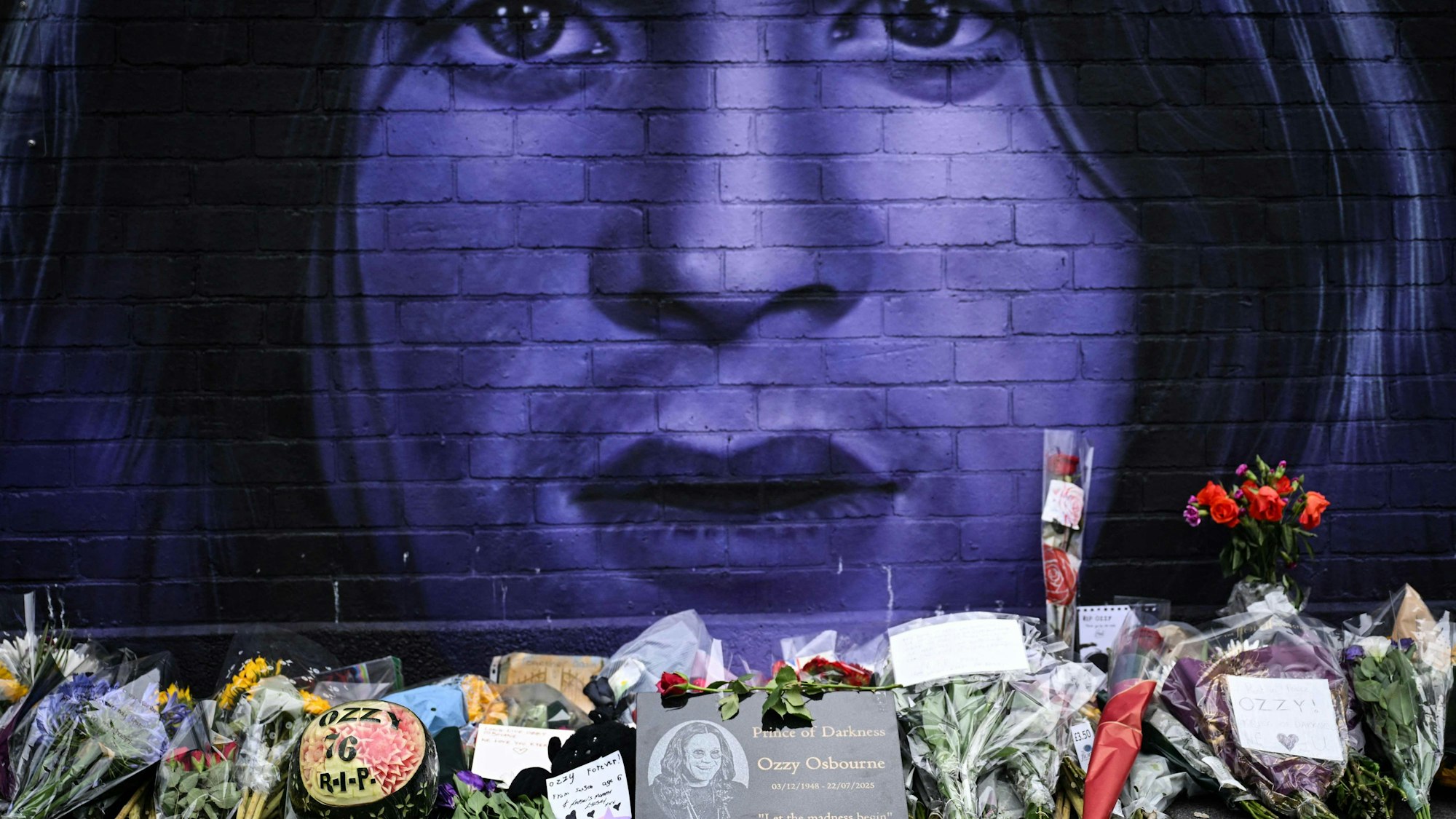 Ein am 23. Juli 2025 aufgenommenes Foto zeigt Blumen, Kerzen und Zeichnungen an einem behelfsmäßigen Mahnmal, das den verstorbenen britischen Sänger und Songwriter Ozzy Osbourne darstellt, in Birmingham.
