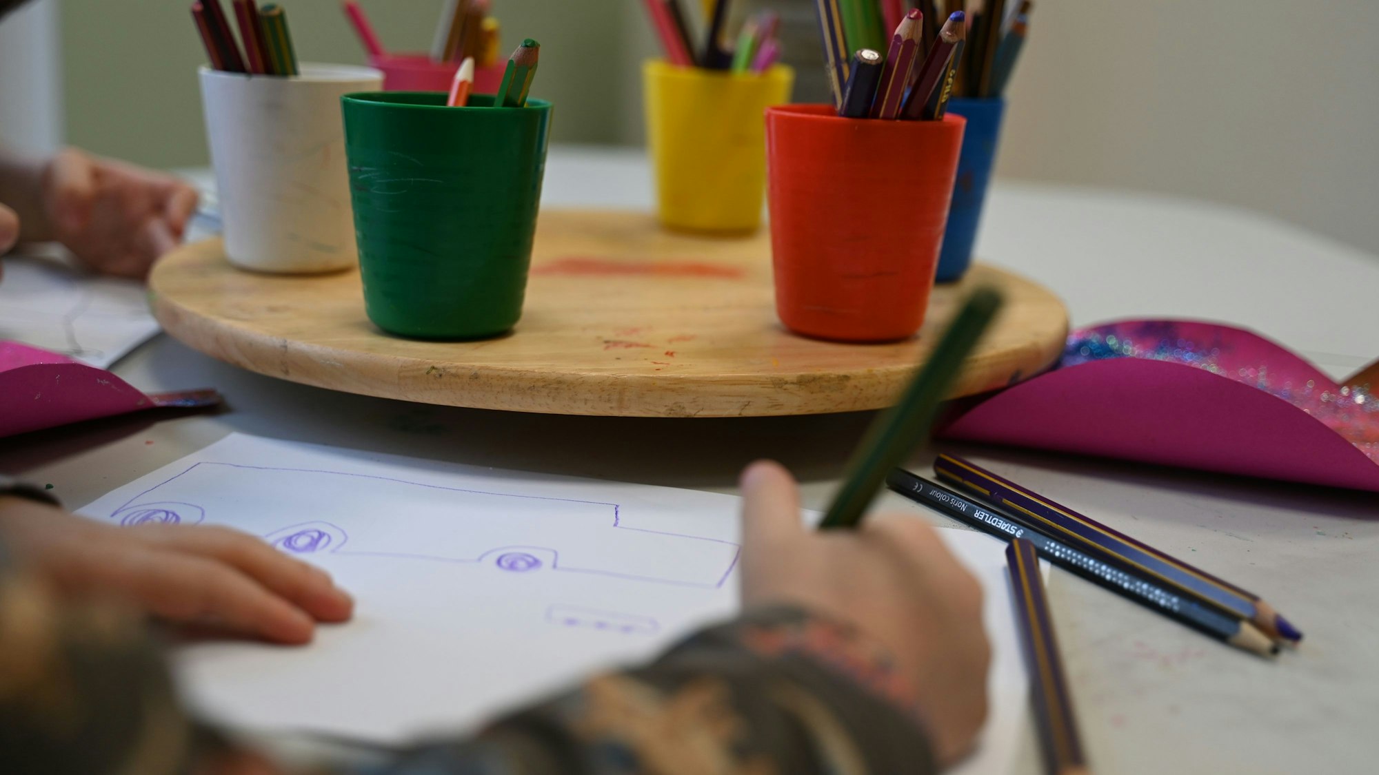 Ein Kind malt ein Bild in einer Kindertagesstätte. Eltern kleiner Kinder müssen sich auch im ab August startenden Kindergartenjahr auf Missstände in der Kitalandschaft einstellen. (Symbolbild)