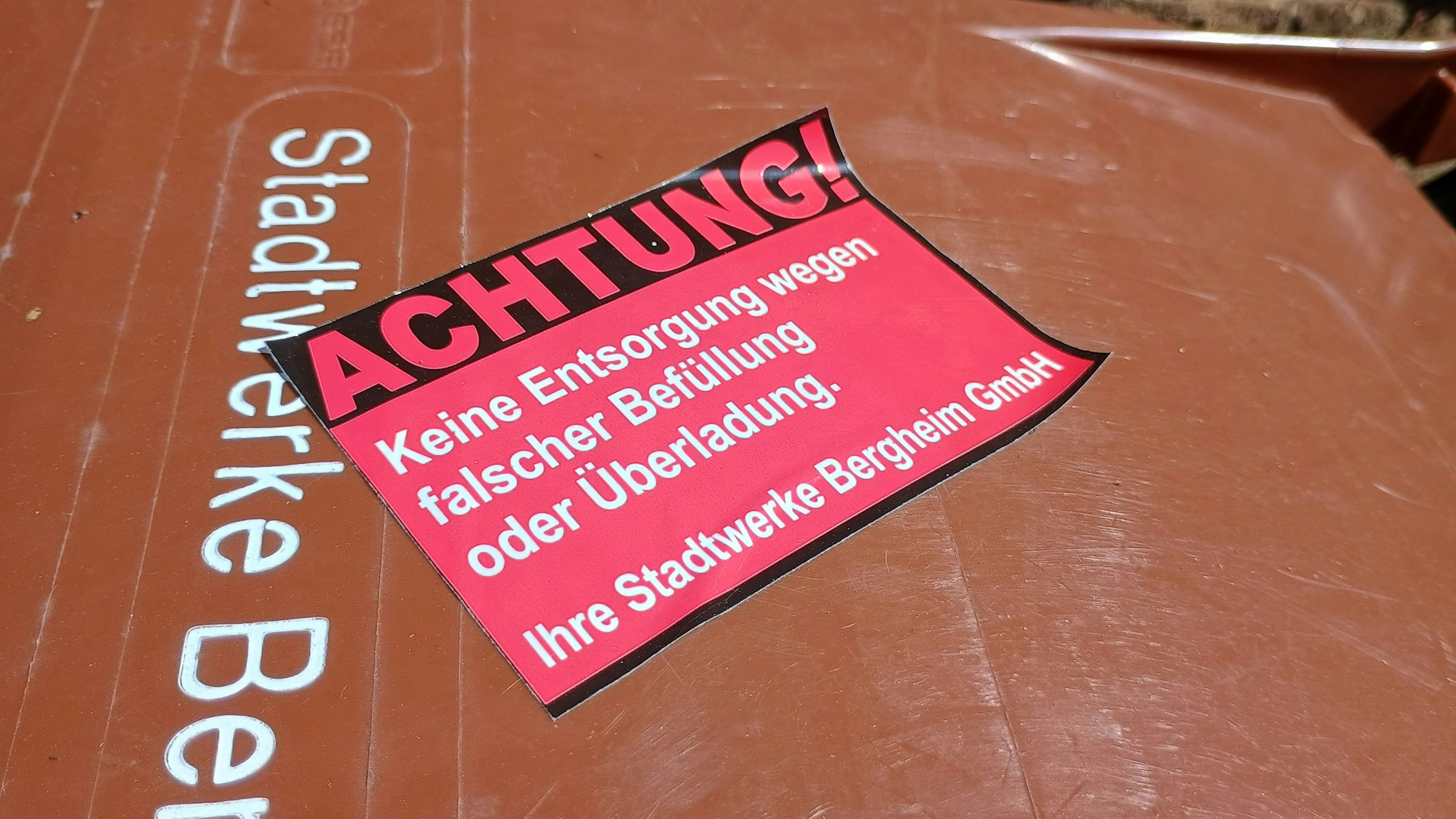 Das bild zeigt den Aufkleber mit der Aufschrift: Achtung! Keine Entsorgung wegen falscher Befüllung oder Überladung. Ihre Stadtwerke Bergheim GmbH