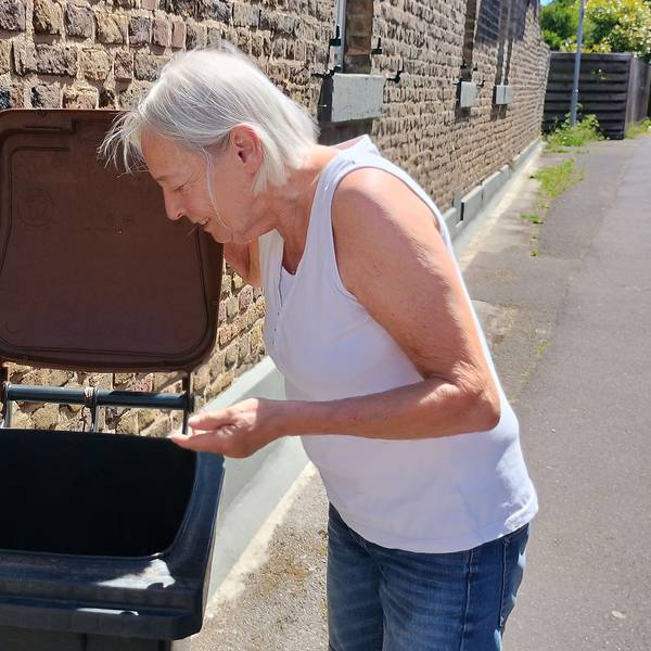 Das Bild zeigt, wie die Seniorin ihre Tonne öffnet und hineinschaut.