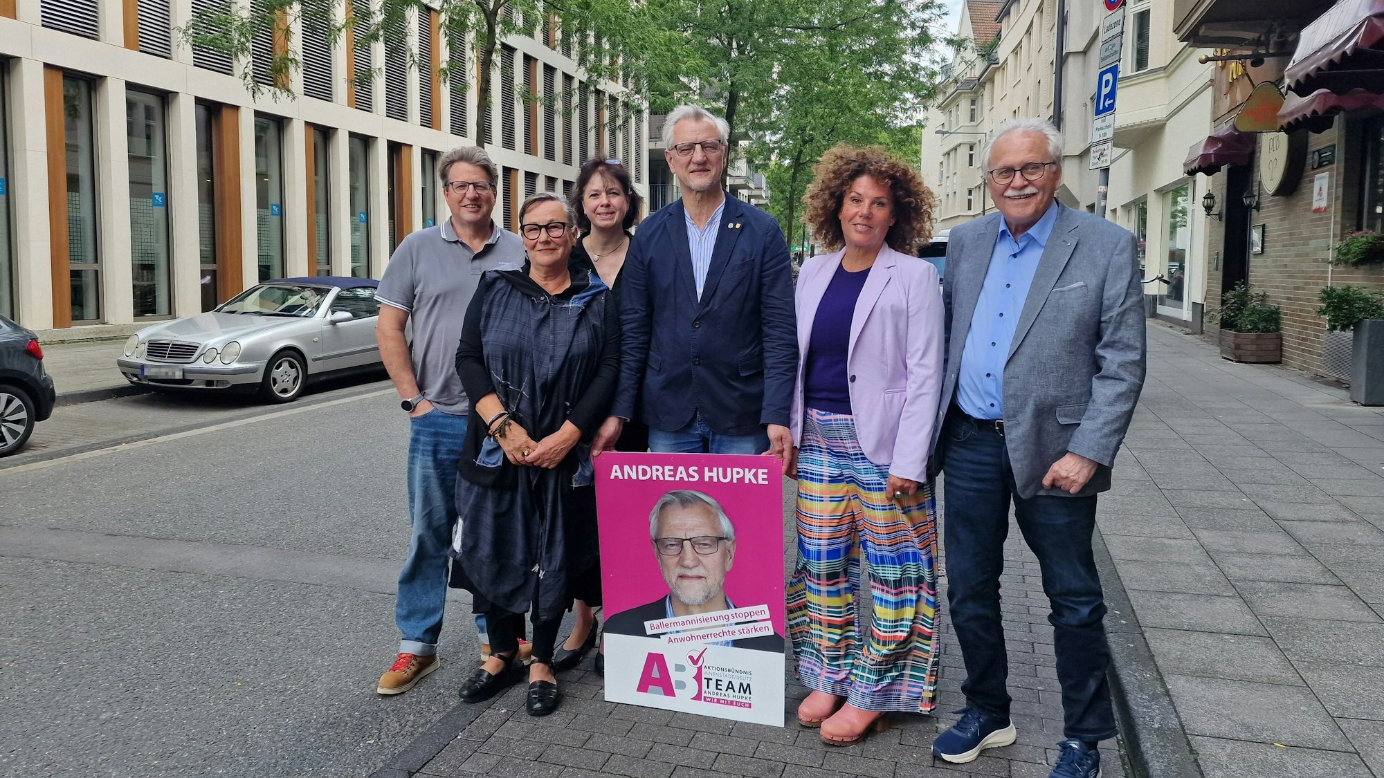 Das Aktionsbündnis von Andreas Hupke posiert mit einem Wahlplakat auf einer Straße in Deutz.