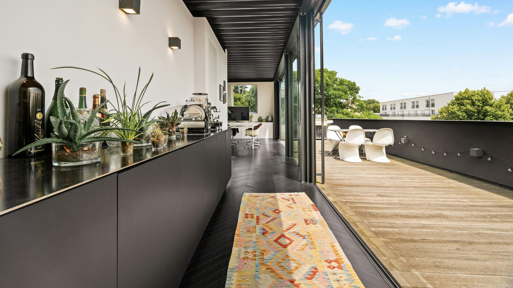 Aufnahme eines offenen Wohnbereichs mit langer Bar und einer mit Holz verlegten Dachterasse.