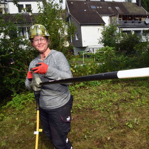 Eine Frau mit einem Rootwave, einem elektrischen Gerät zur Pflanzenbekämpfung, in der Hand.