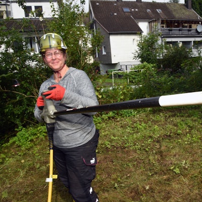 Eine Frau mit einem Rootwave, einem elektrischen Gerät zur Pflanzenbekämpfung, in der Hand.
