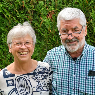 Annegret und Christoph Schmitz stehen vor einer Hecke. Er hat seinen Arm um sie gelegt.