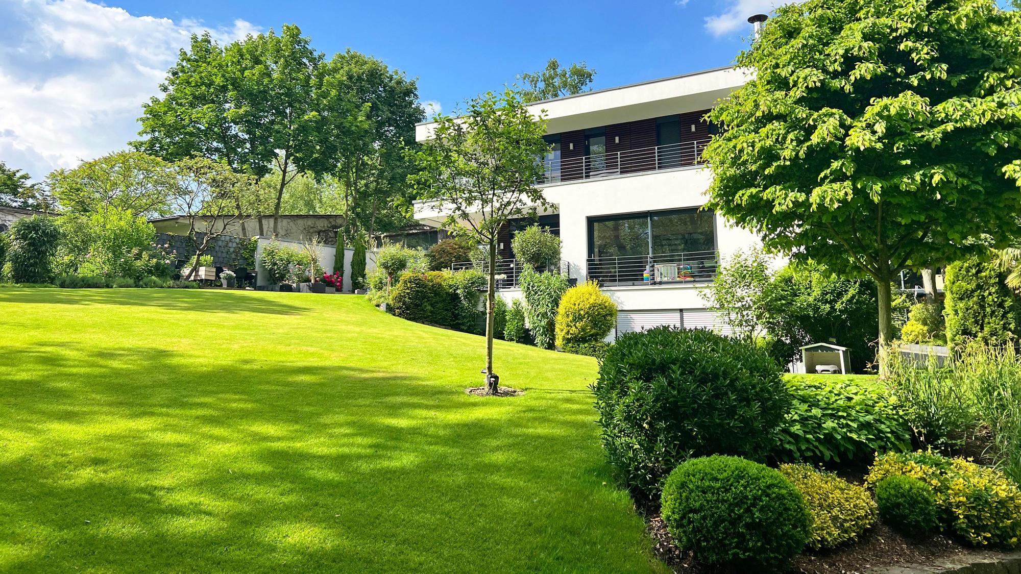 Am Hang gelegene Gartenanlage mit Haus im Hintergrund