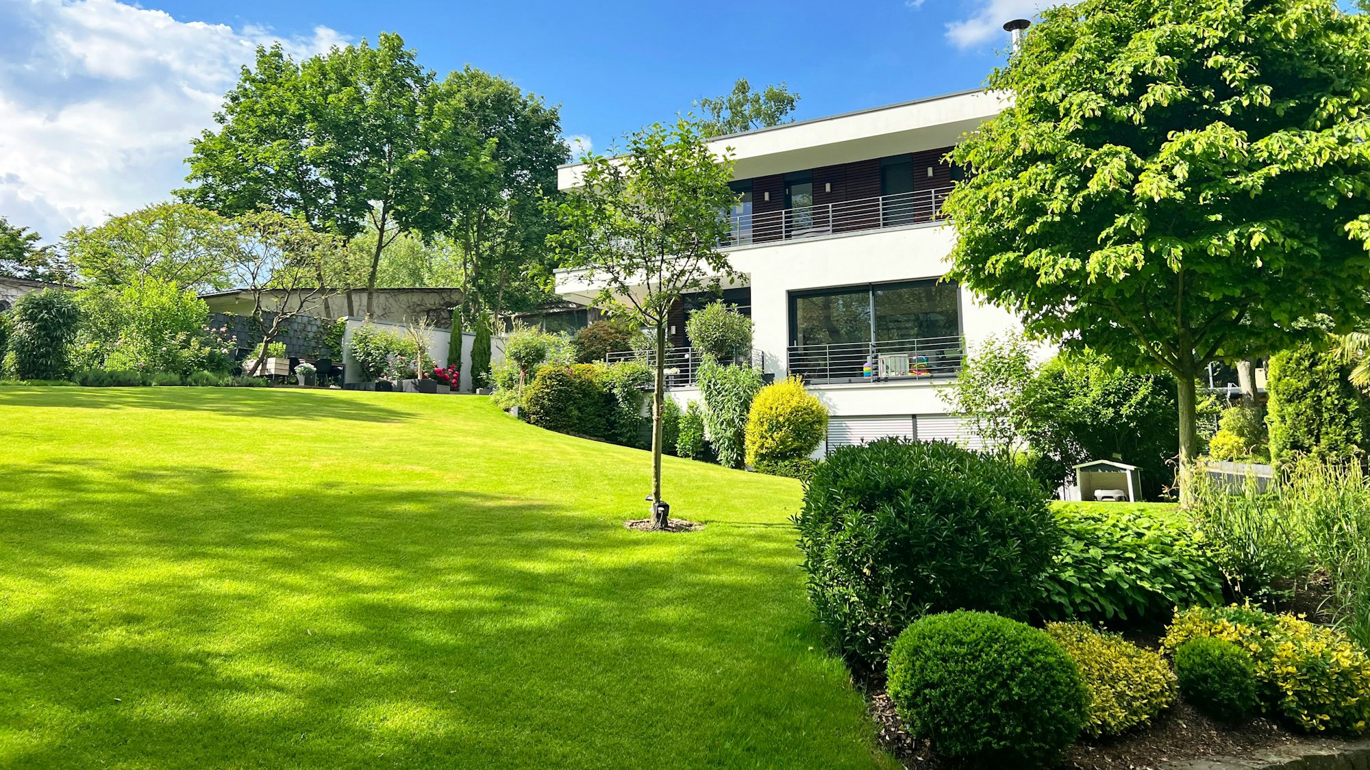 Am Hang gelegene Gartenanlage mit Haus im Hintergrund