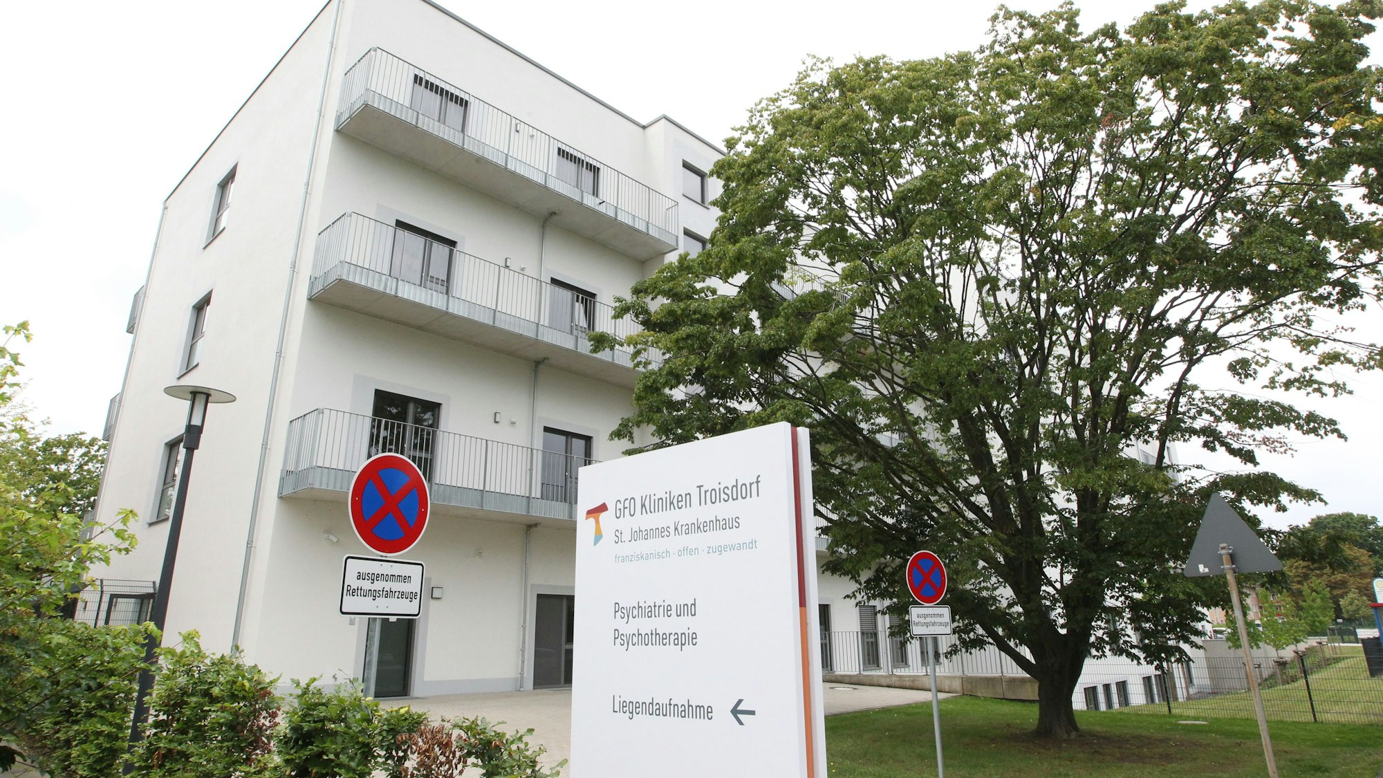 Ein moderner Klinikneubau. Auf einem Hinweisschild steht Psychiatrie und Psychotherapie.