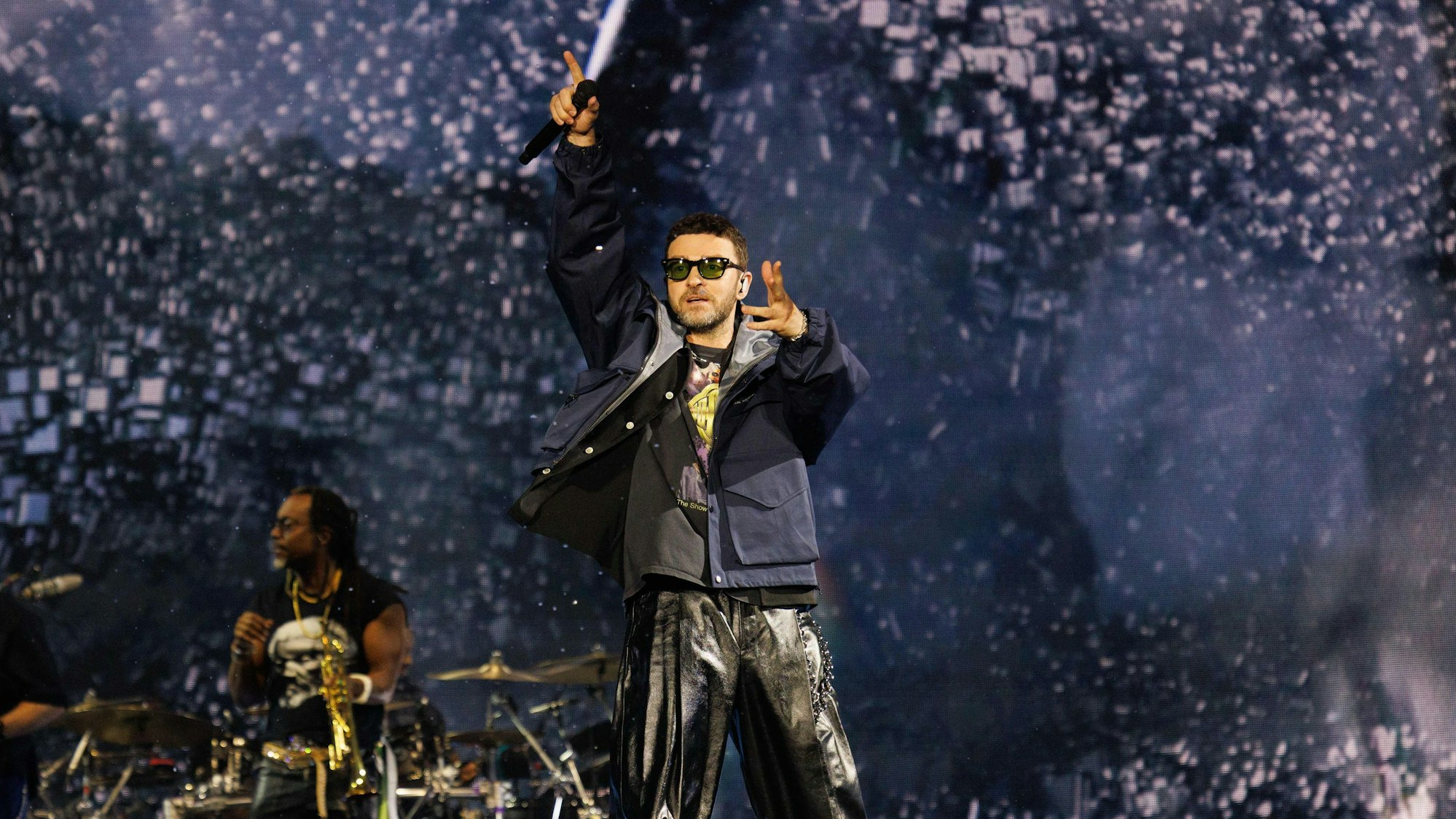 Der Sänger Justin Timberlake singt auf einer Bühne in ein Mikrofon.