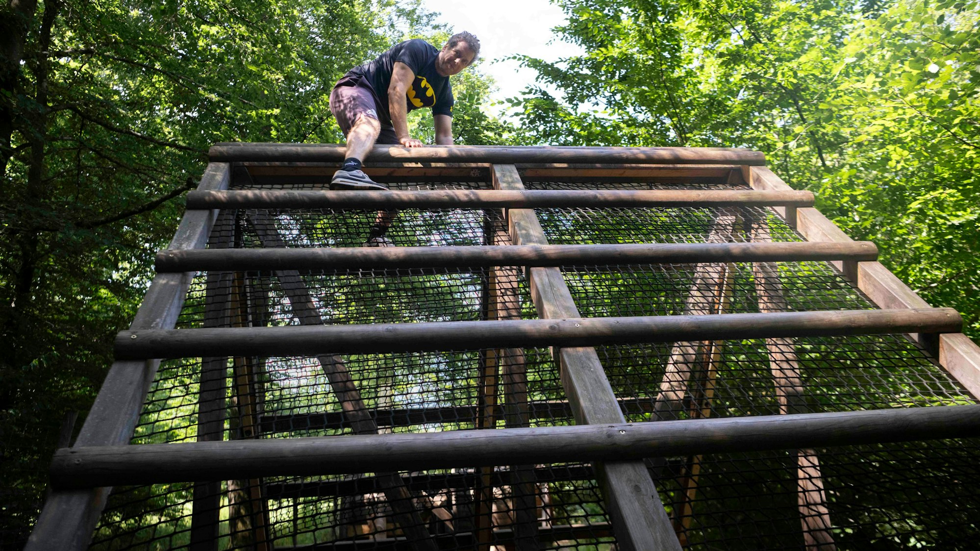 Ein Mann klettert im Arboretum in Nettersheim über ein Hindernis.