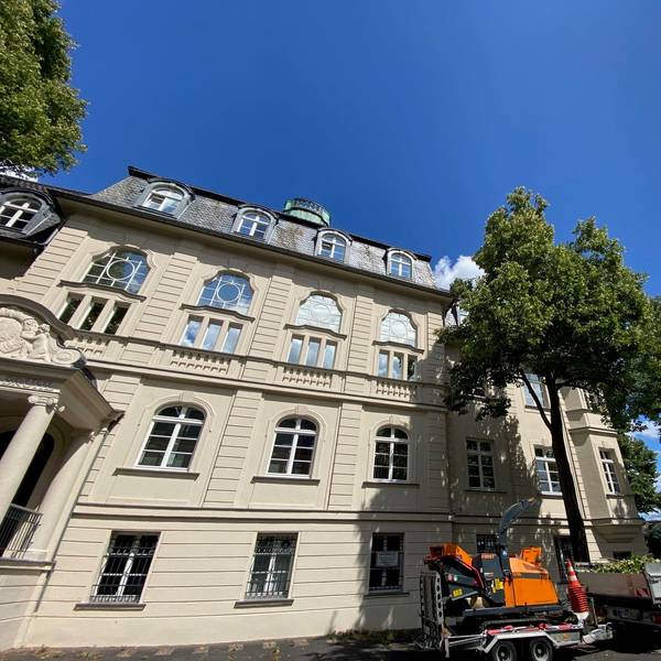 Zu sehen ist ein weißes Gebäude vor blauem Himmel.
