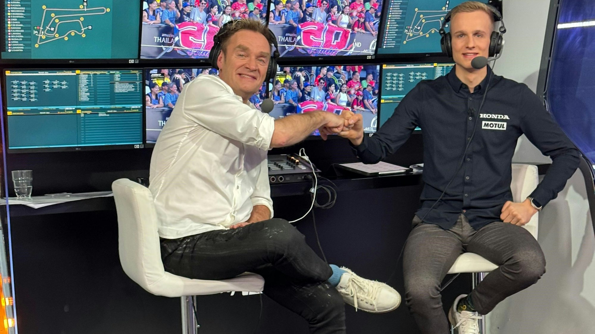 Zwei Männer sitzen in einer Kommentatorenkabine des Fernsehsenders Sky nebeneinander.