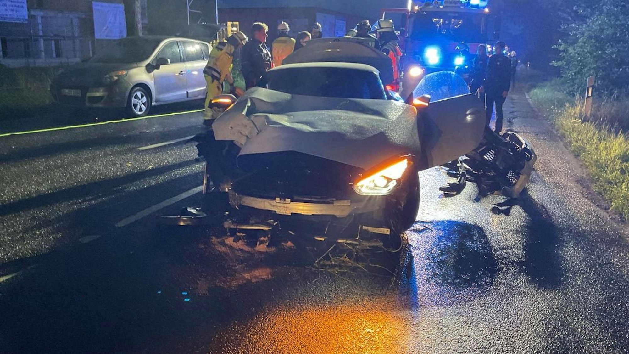 Ein stark beschädigtes Auto steht nach einem Unfall auf einer Straße.