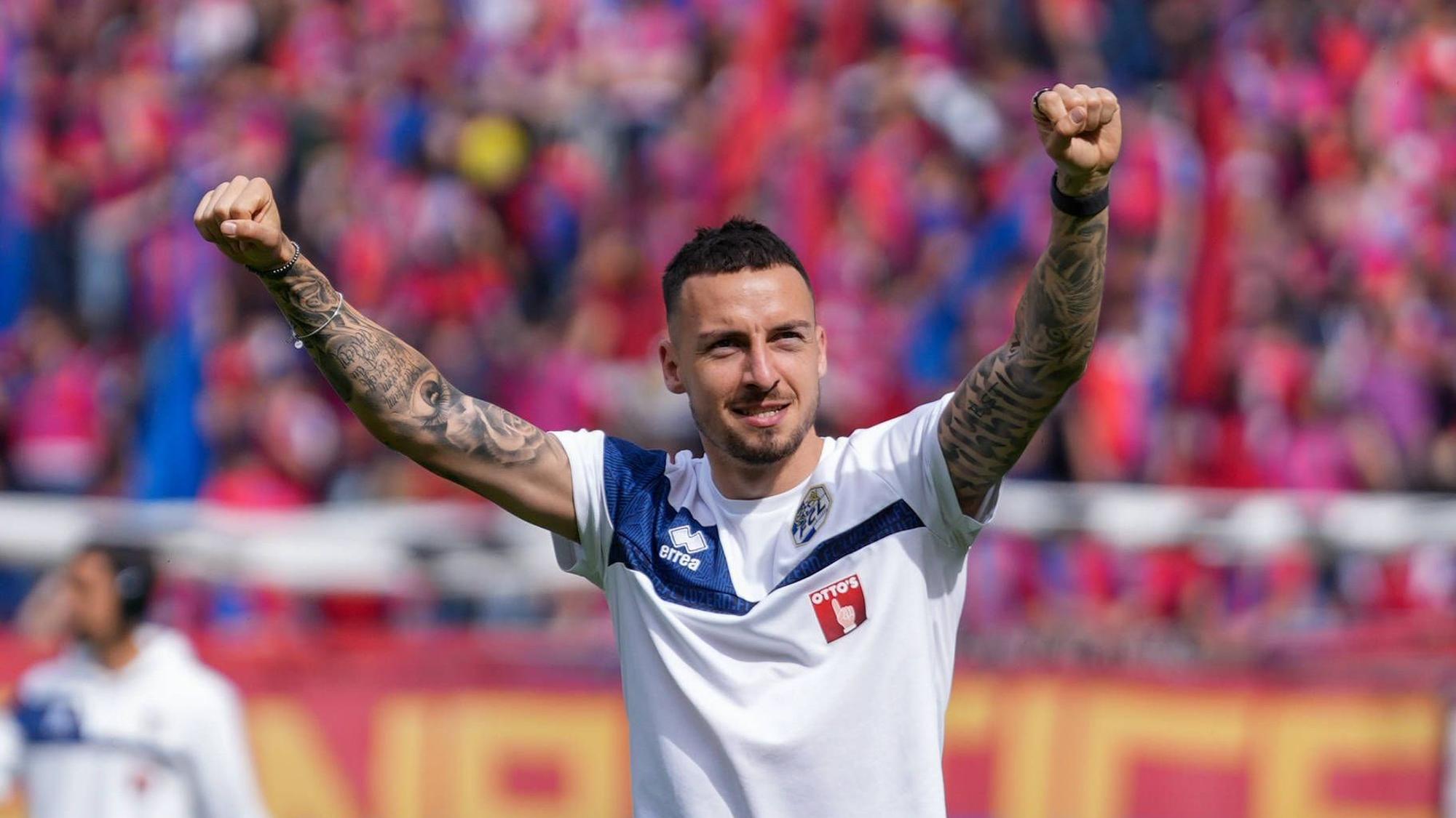 Fußballer Sinan Karweina streckt die Arme jubelnd in die Höhe.