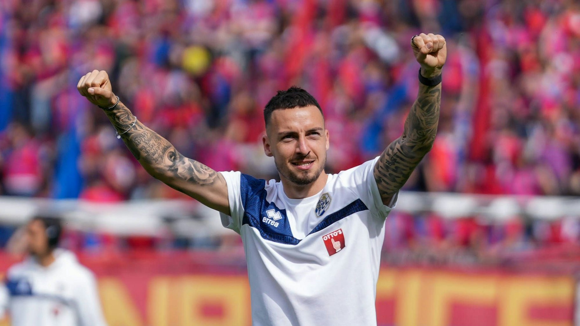 Fußballer Sinan Karweina streckt die Arme jubelnd in die Höhe.