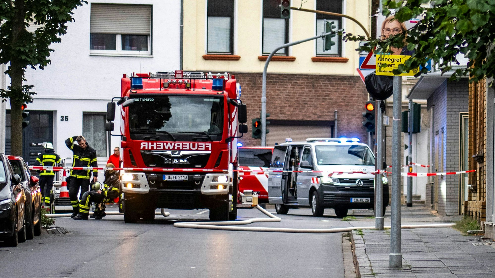 Eine Straße in Euskirchen ist mit rot-weißem Flatterband abgesperrt. Innerhalb der Absperrung stehen ein Feuerwehrfahrzeug sowie einige Feuerwehrleute.