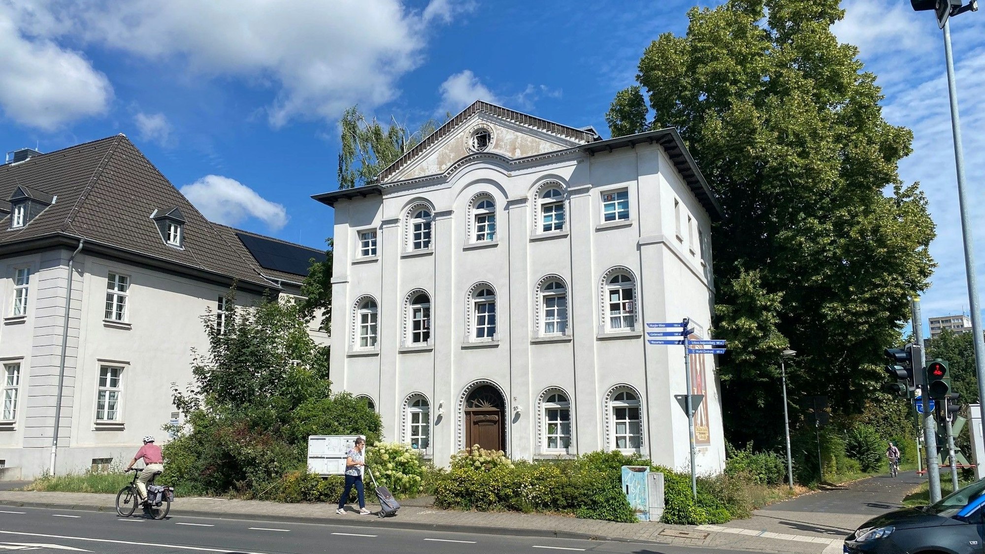 Zu sehen ist ein weißes Haus an einer Straße.