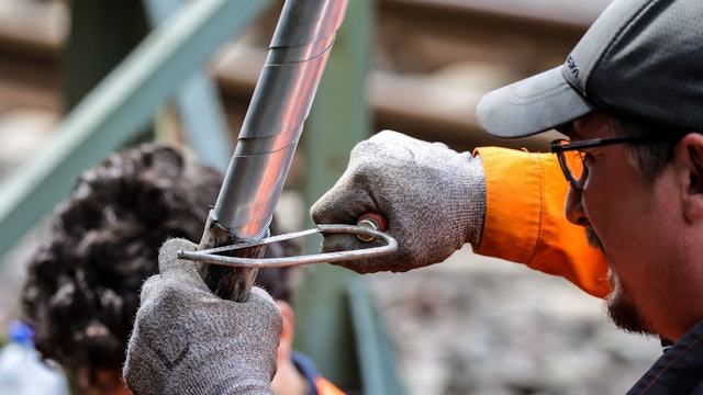 Ein Bahn-Mitarbeiter repariert ein dickes Kabel an der Stelle, wo im August ein Brandanschlag stattgefunden hat. An der wichtigen Nord-Süd-Strecke der Deutschen Bahn in Düsseldorf ist wenige Tage später noch ein zweiter Brandsatz gezündet worden.