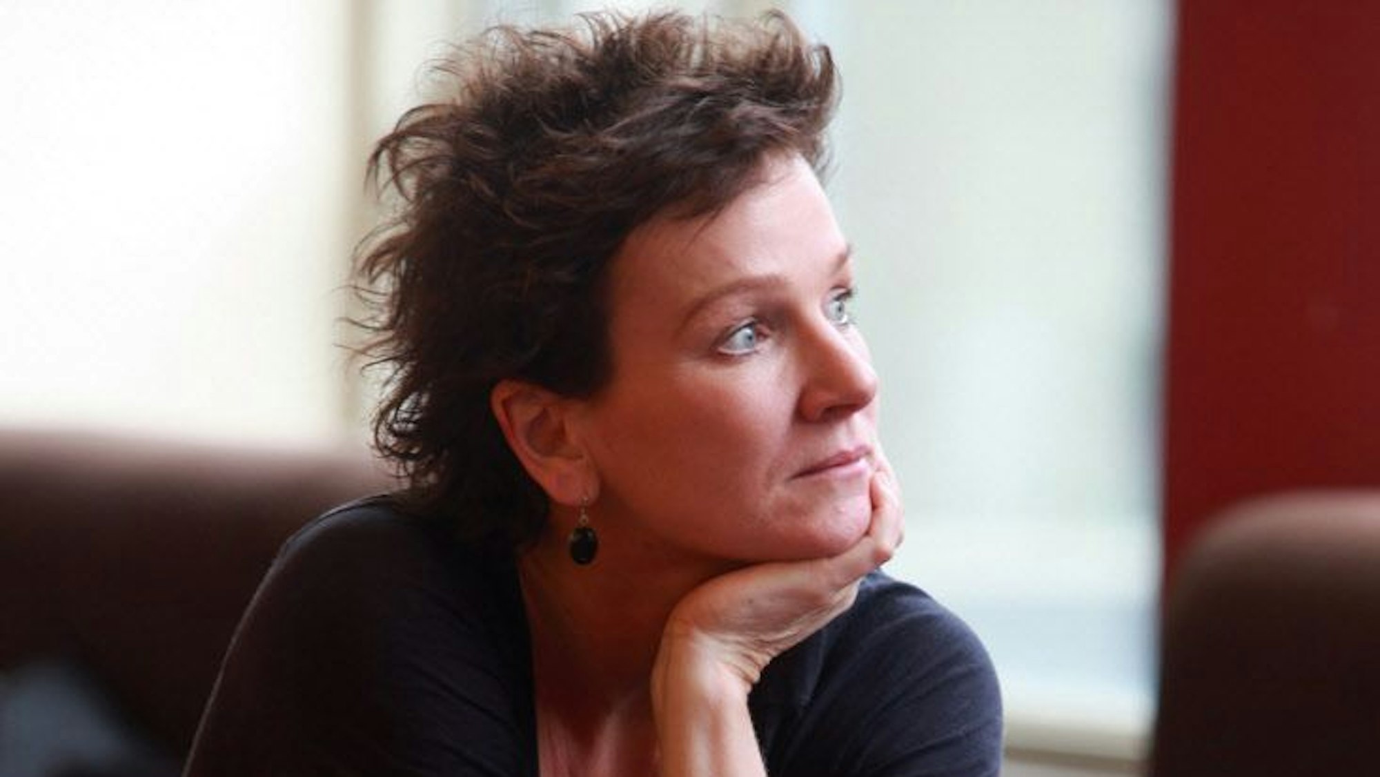 Karin Beier im Halbprofil, den Kopf auf die Hand abgestützt.