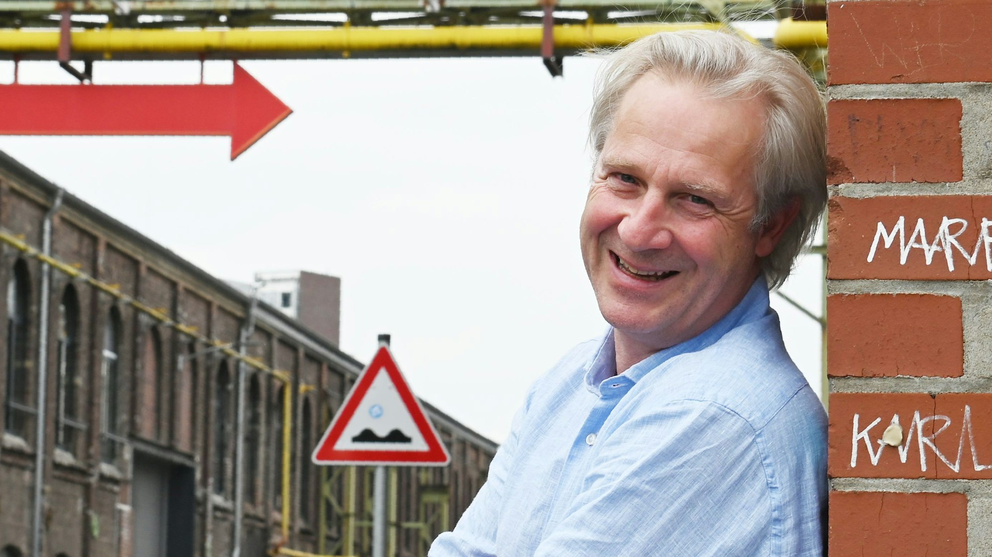 Stefan Bachmann lacht, an eine Mauer des Mülheimer Depots gelehnt.