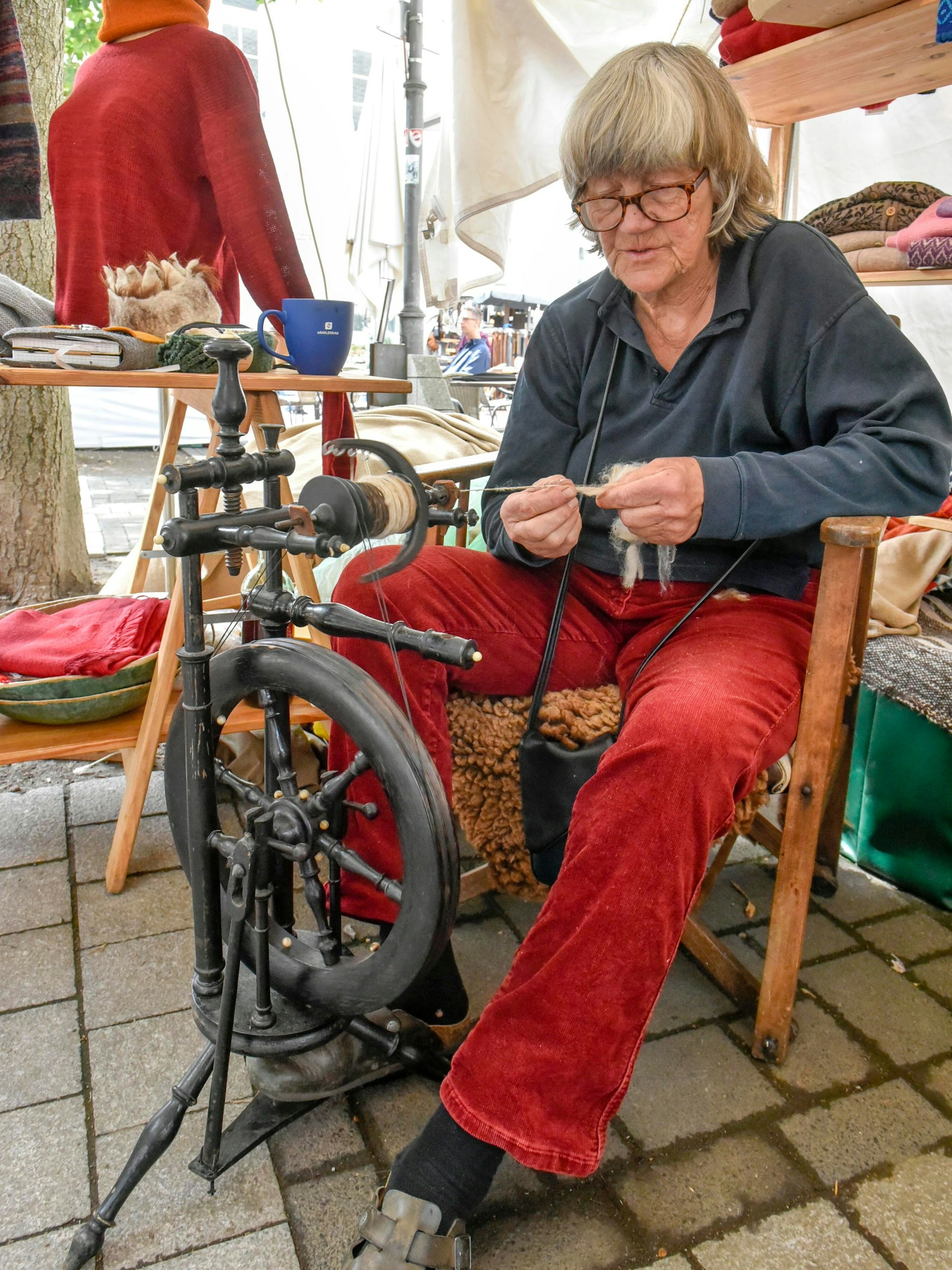 Eine Frau sitzt an einem Spinnrad.