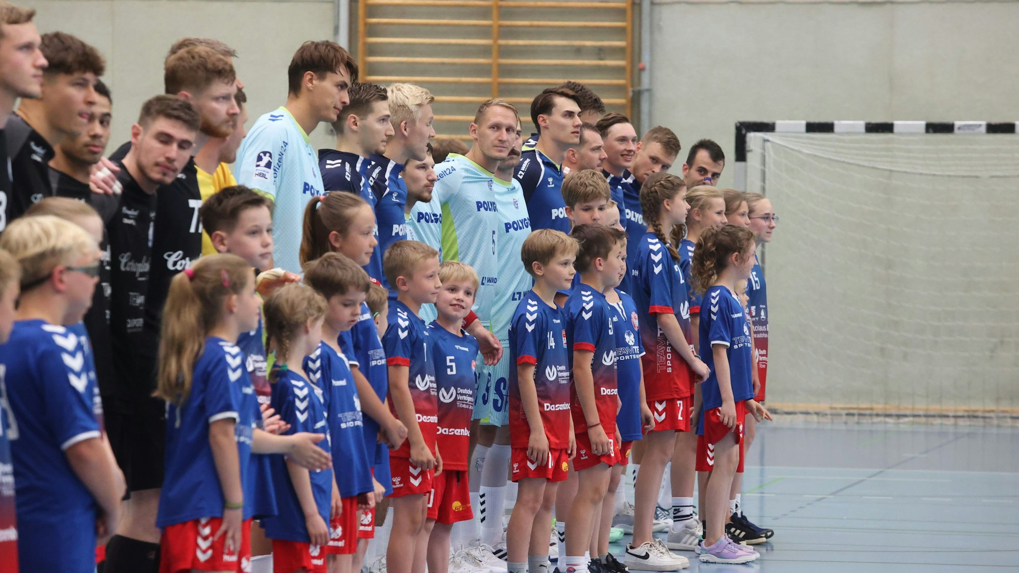 Kinder laufen mit Handball-Profis des VfL Gummersbach und des BHC bei einem Testspiel in Remscheid ein.
