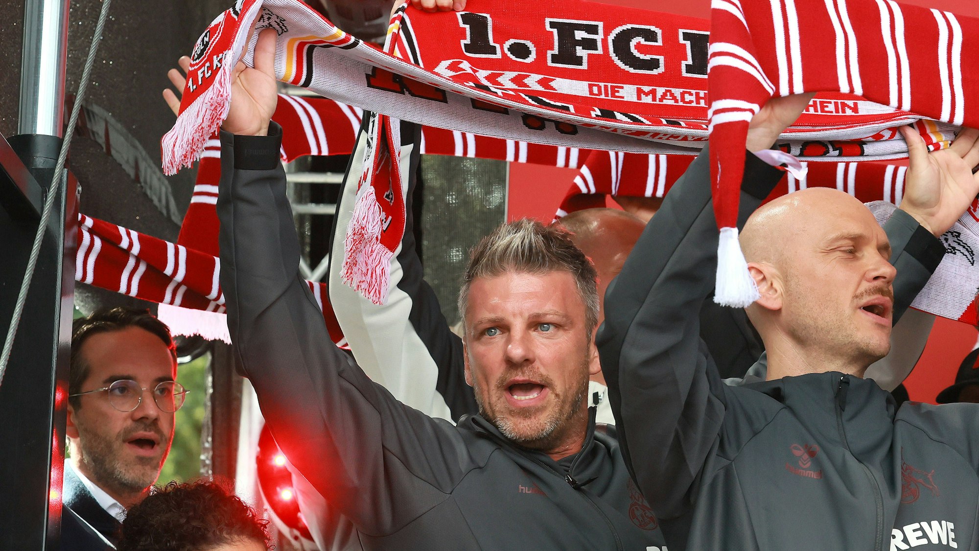 Kwasniok steht auf der Bühne und hält einen Schal nach oben.