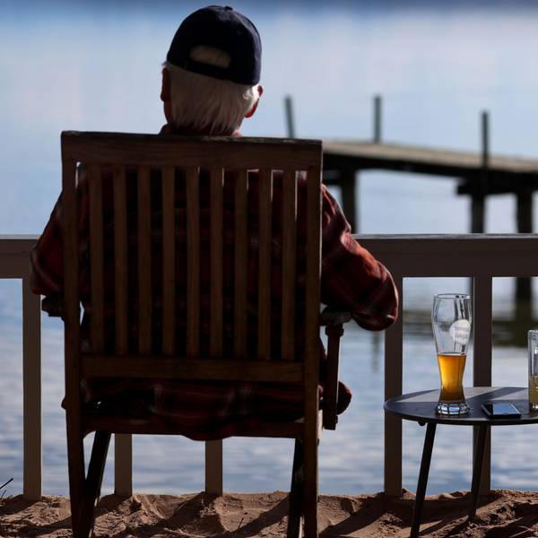 Ein Ausflügler sitzt in einem Biergarten am Ammersee im Sonnenschein, neben ihm steht ein Bier auf einem Tisch.