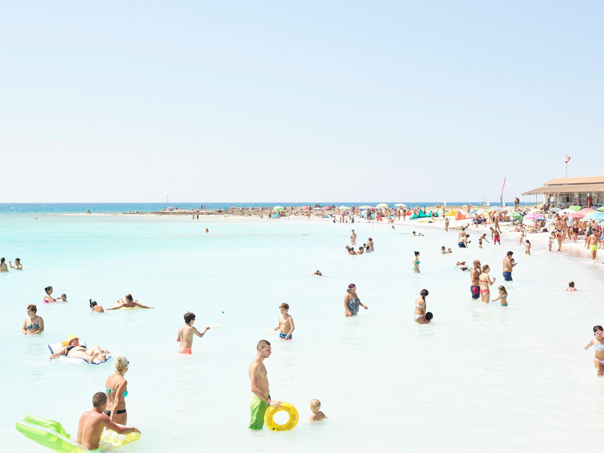 Menschen baden im Meer und liegen am Strand.