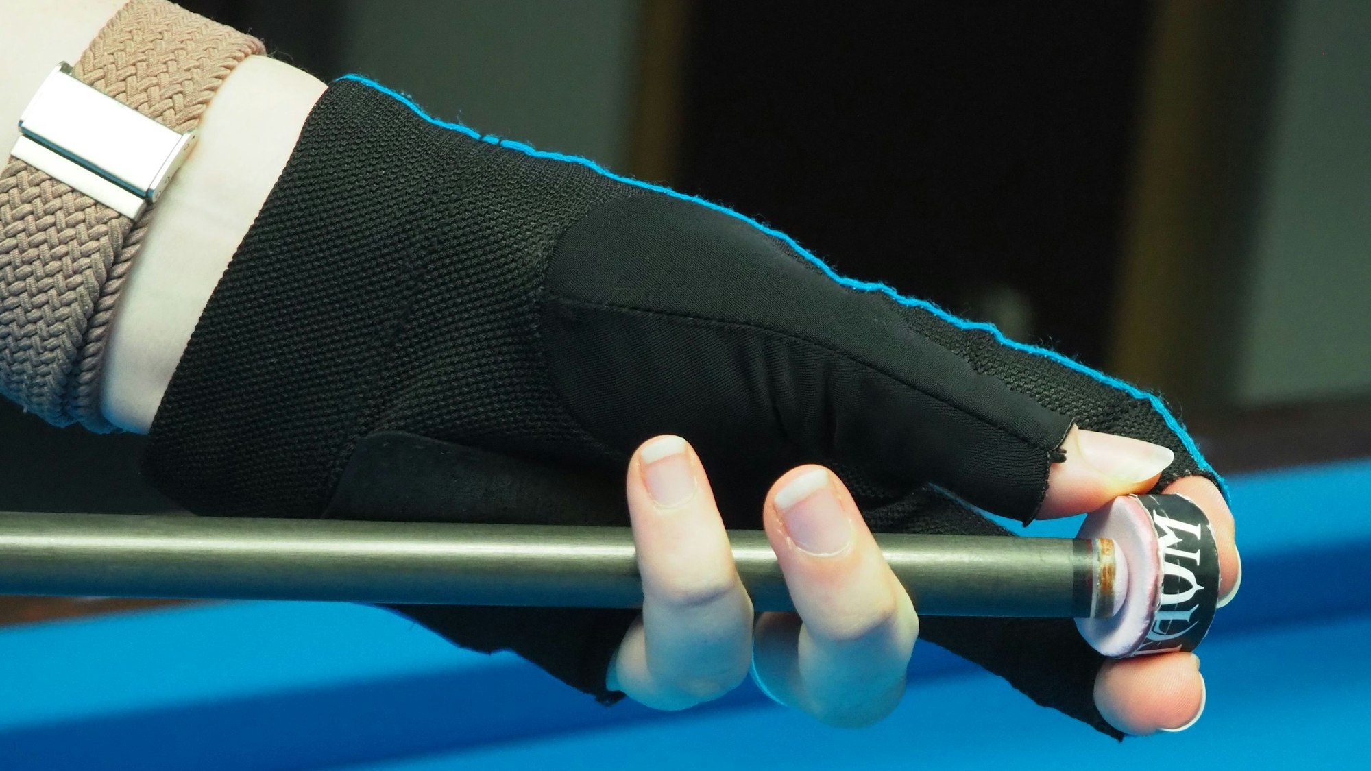 Auf dem Bild ist eine Hand zu sehen, die einen Kreidewürfel und die Spitze eines Queues hält.