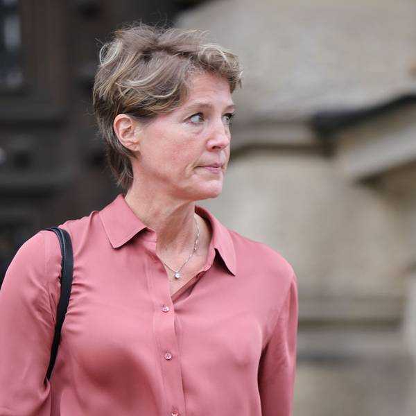 Christina Block schaut auf etwas, das außerhalb des Bildausschnittes liegt. Im Hintergrund befindet sich das unscharf gestellte Strafjustizgebäude in Hamburg.