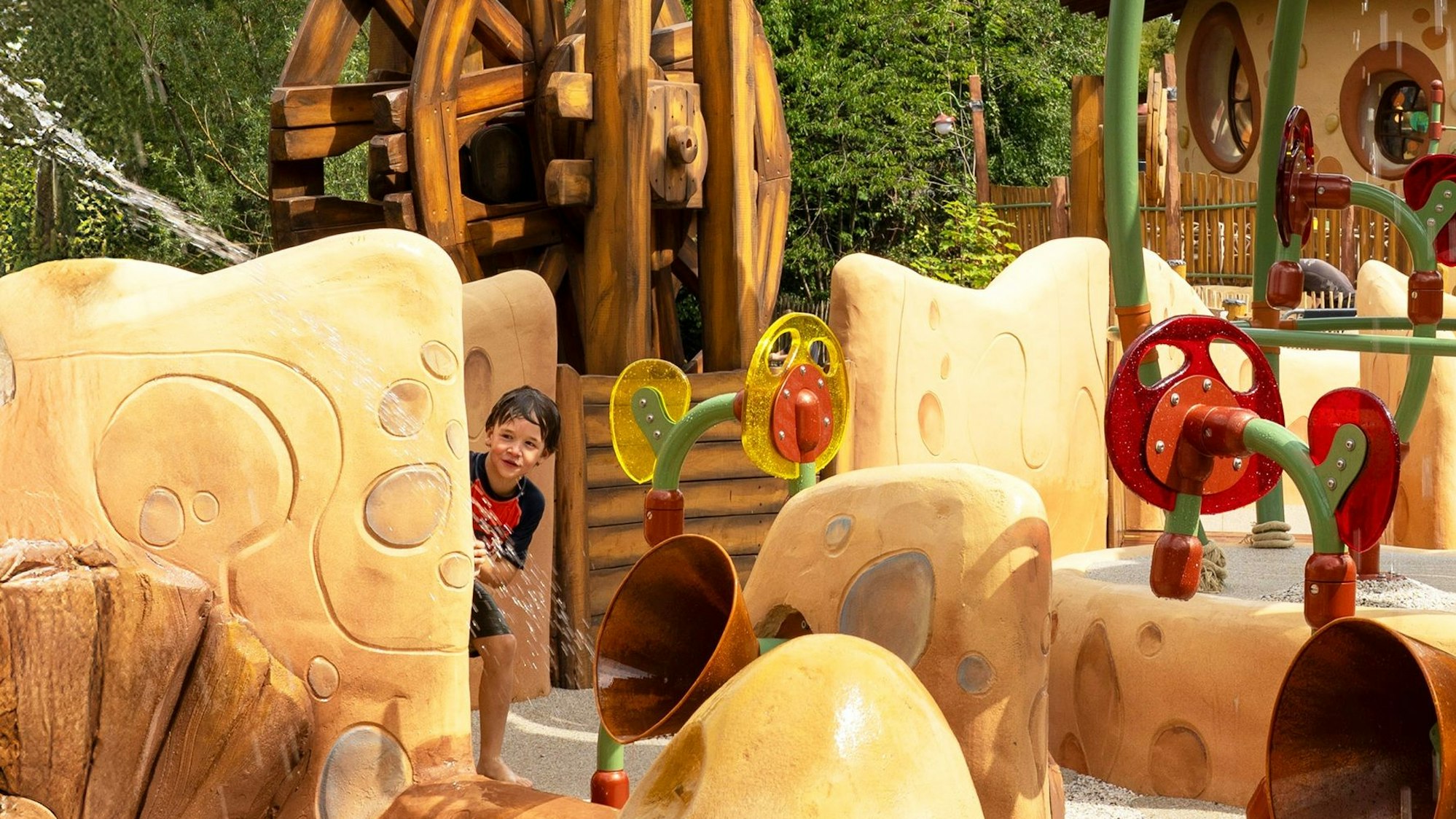 Das Bild zeigt einen Wasserparcours und einen kleinen Jungen, der sich versteckt hat.