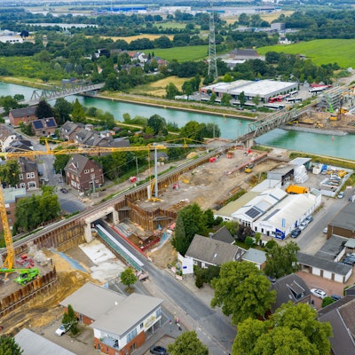 22.07.2025, Nordrhein-Westfalen, Voerde: Kräne und Baufahrzeuge an der Bahn-Baustelle im Bereich Bahnhof Voerde. (Luftbild mit einer Drohne) Die rund 73 Kilometer lange Strecke von Oberhausen nach Emmerich ist ein Teilstück des europäischen Güterverkehrskorridors vom Nordseehafen Rotterdam bis nach Genua am Mittelmeer. Seit November 2024 ist die Strecke wegen der Bauarbeiten 80 Wochen lang gar nicht oder nur eingeschränkt befahrbar. Foto: Christoph Reichwein/dpa +++ dpa-Bildfunk +++