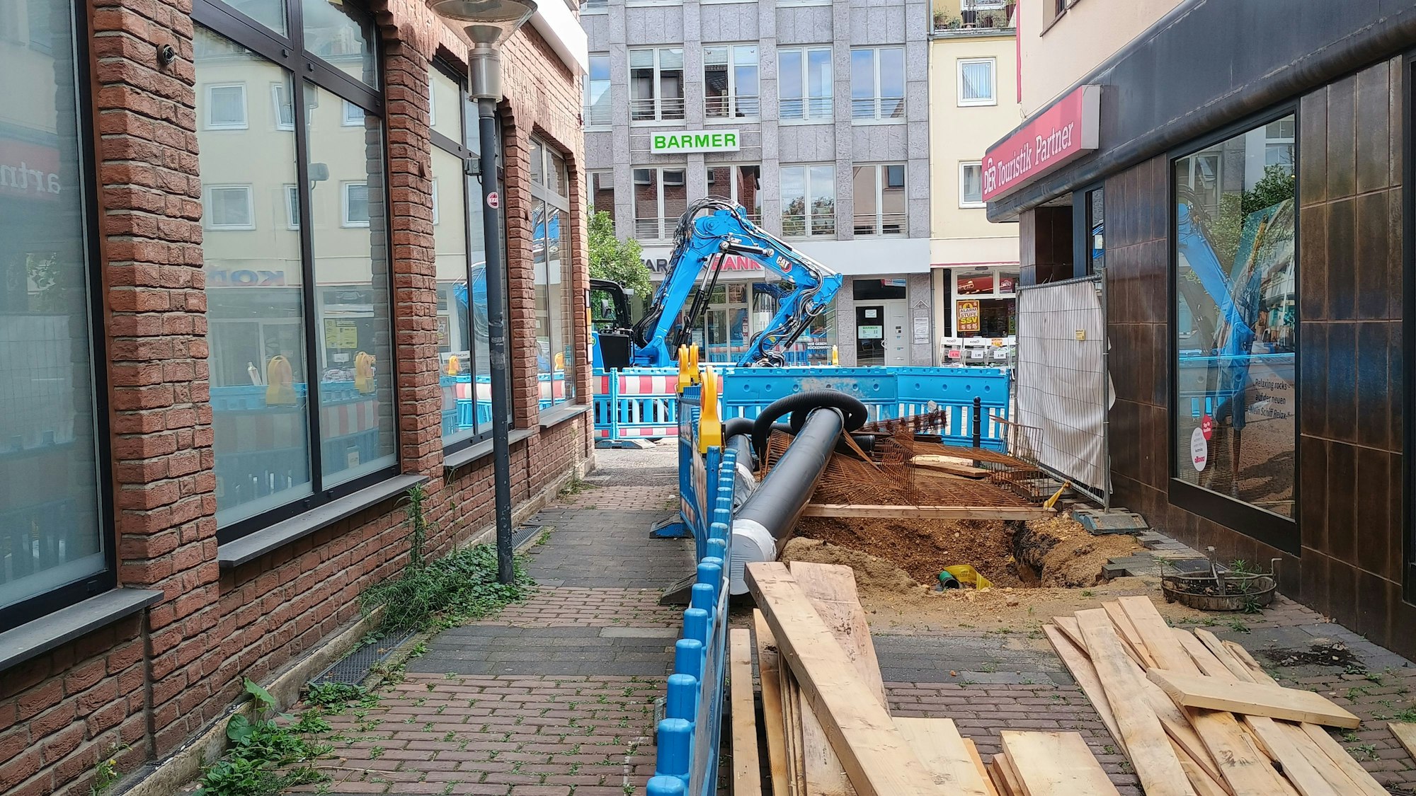Das Bild zeigt den aufgebrochenen Boden an der Gasse, drumherum Bauzäune.