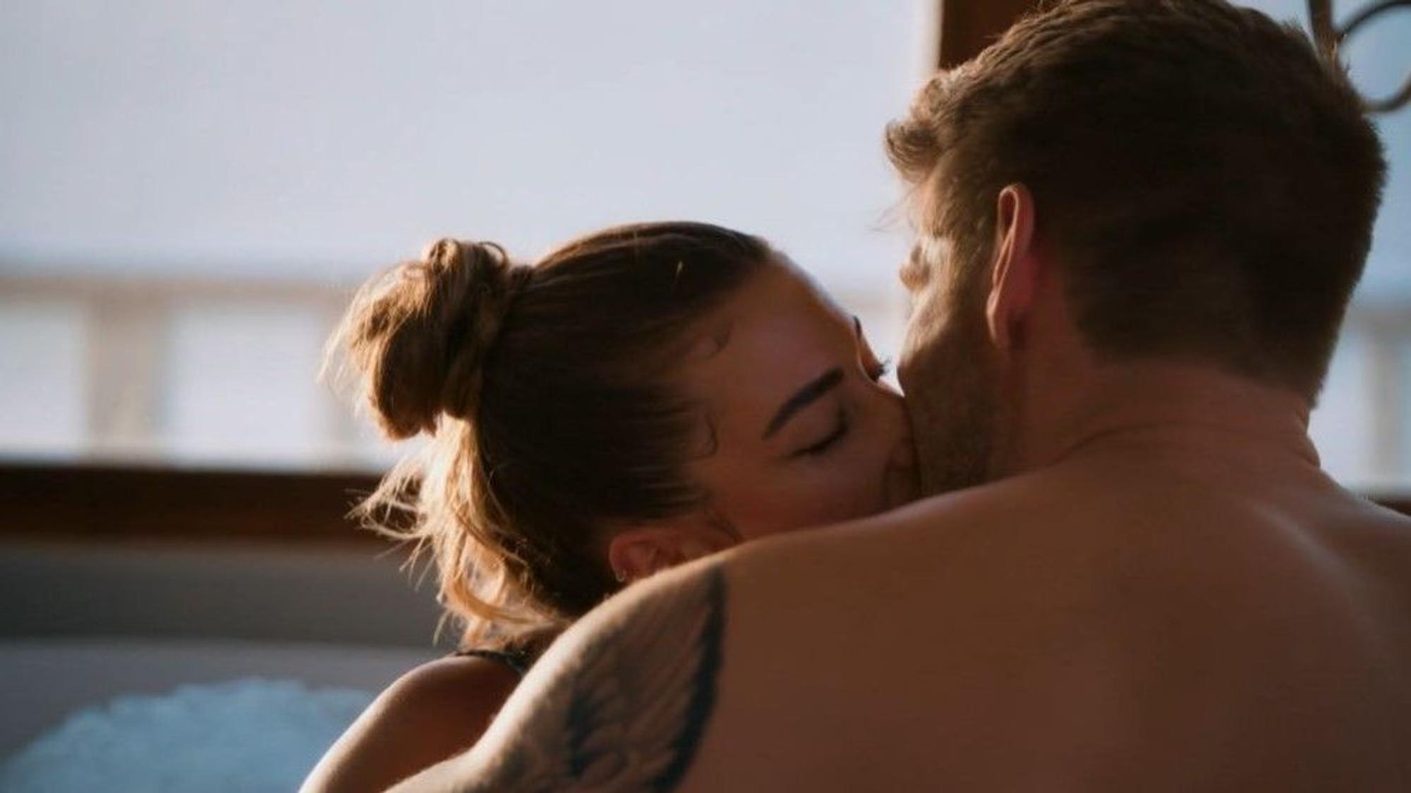 Lena und Martin küssen sich innig in einer Badewanne.