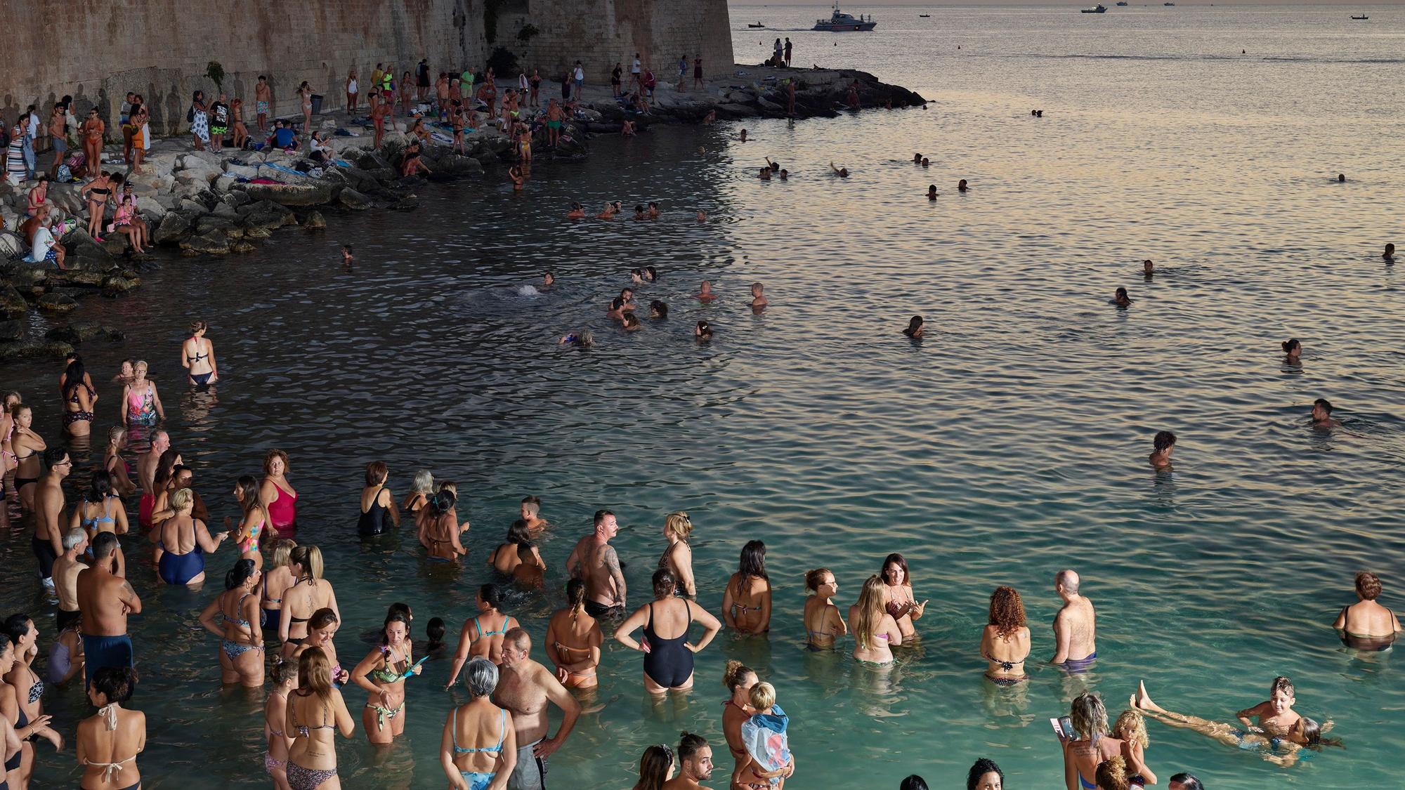 Menschen stehen im Wasser und warten auf den Sonnenuntergang