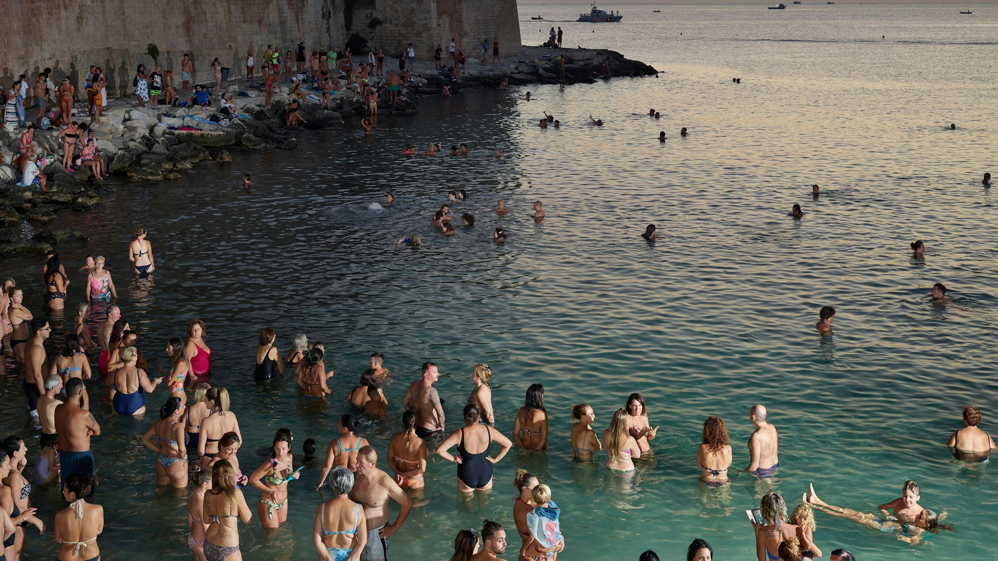Menschen stehen im Wasser und warten auf den Sonnenuntergang