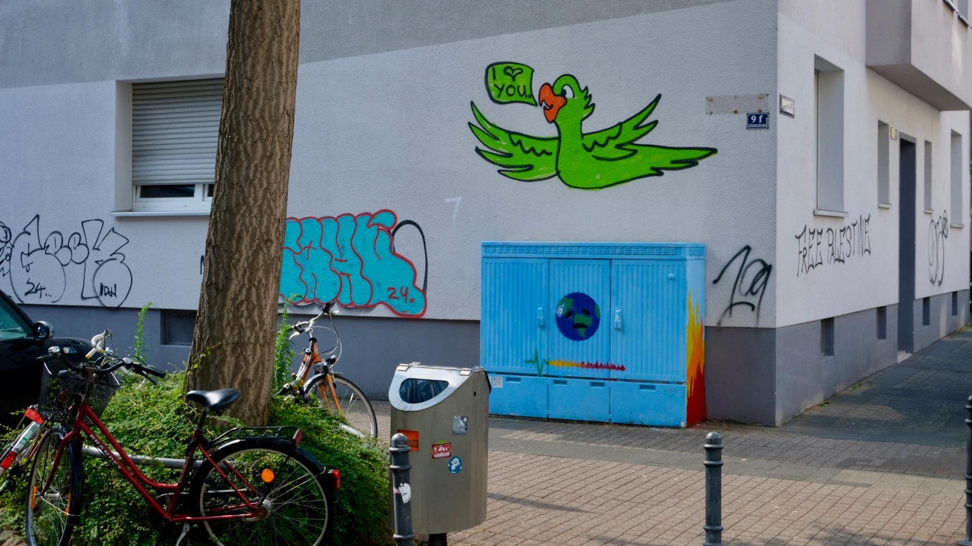 An einer Hauswand schwebt ein Kakadu und andere Schmierereien.