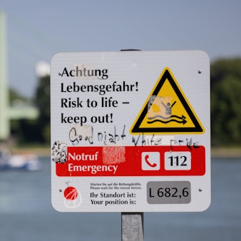 30.05.2023, Nordrhein-Westfalen, Köln: Ein Hinweisschild mit der Aufschrift „Achtung Lebensgefahr“ weist am Rhein in Rodenkirchen auf die Gefahren beim Schwimmen in dem Fluss hin