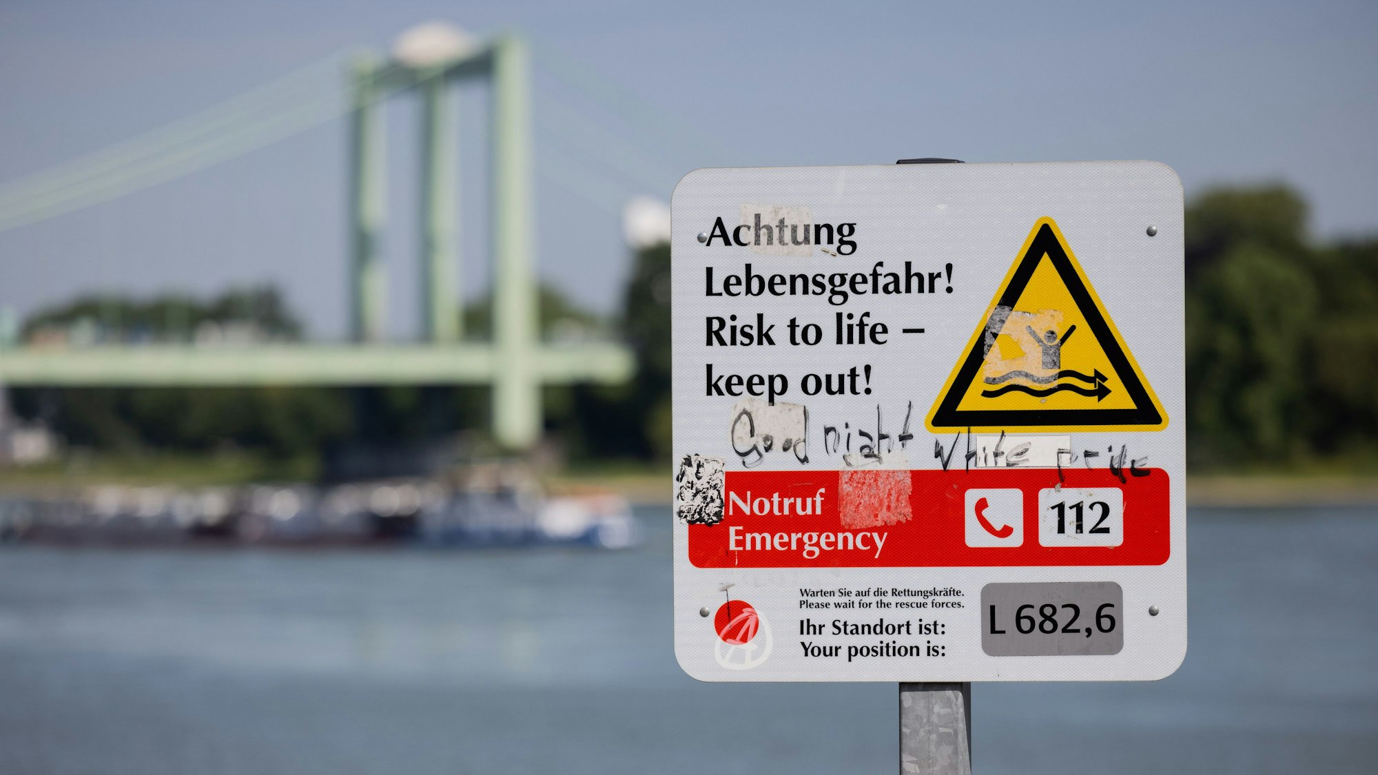 30.05.2023, Nordrhein-Westfalen, Köln: Ein Hinweisschild mit der Aufschrift „Achtung Lebensgefahr“ weist am Rhein in Rodenkirchen auf die Gefahren beim Schwimmen in dem Fluss hin