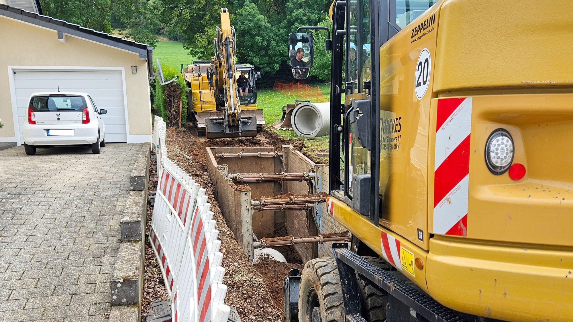 Zwei Bagger heben von beiden Seiten einen Graben aus, in denen große Kanalrohre gelegt werden.