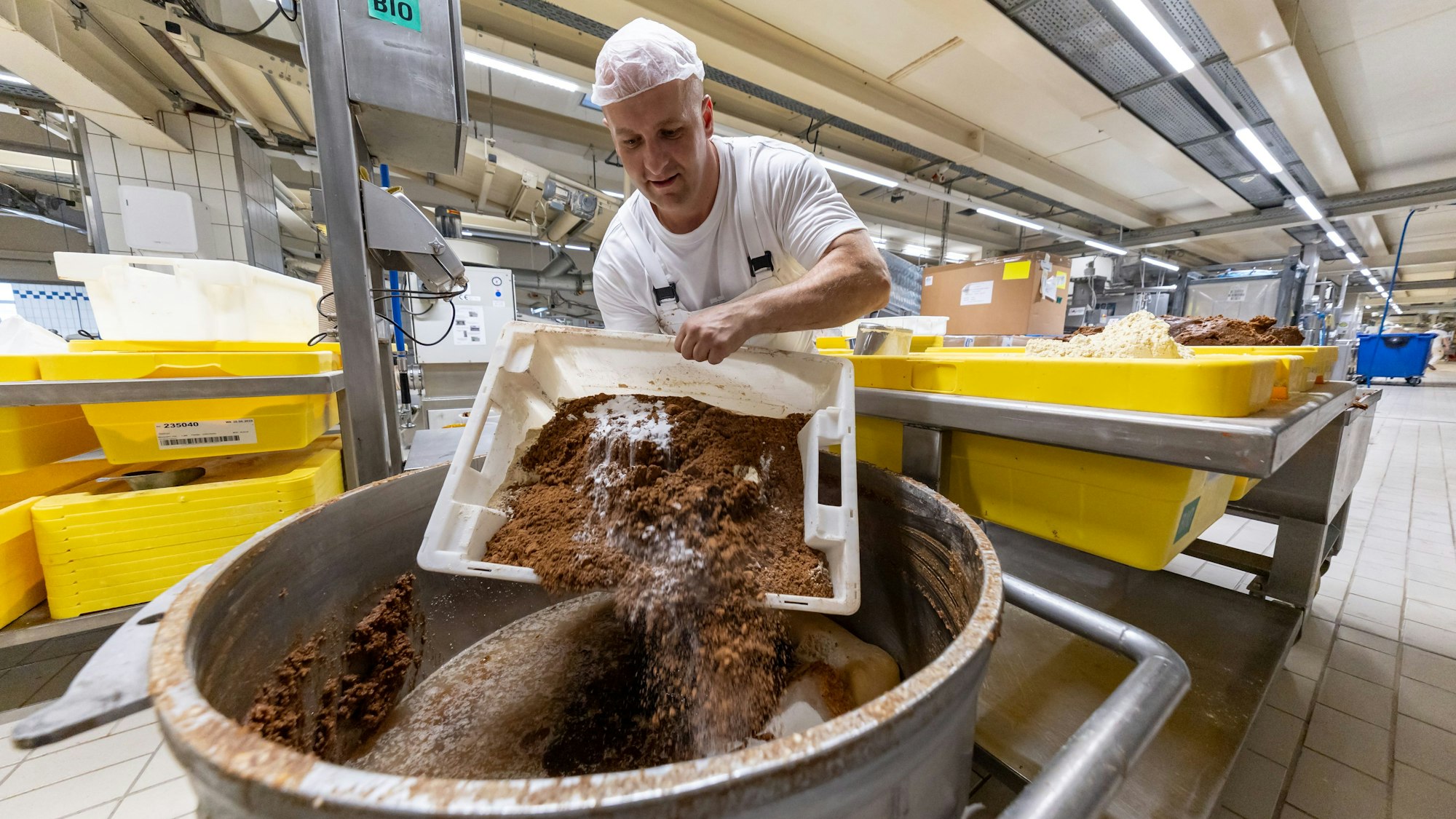Ein Mitarbeiter des Lebkuchenherstellers Schmidt kippt in der Produktion verschiedene Rohstoffe zur Herstellung von Lebkuchenmasse in einen Behälter.