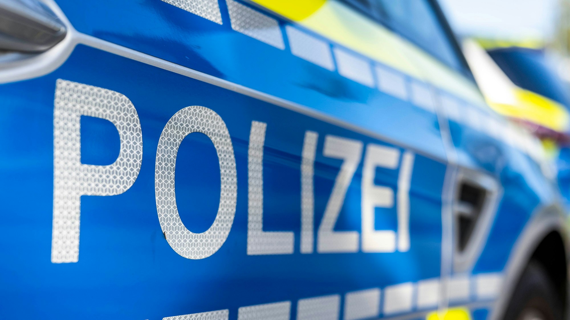 An der Tür von einem Streifenwagen steht der Schriftzug „Polizei“